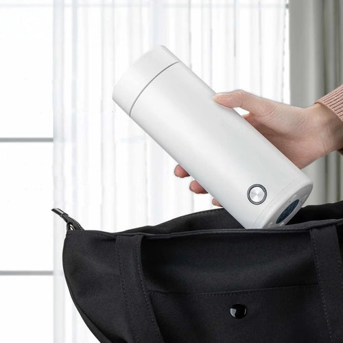 Person holding a white cylindrical device next to a black bag.