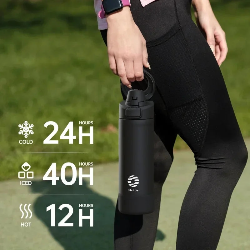 Person holding a black water bottle with temperature retention graphics in an outdoor setting